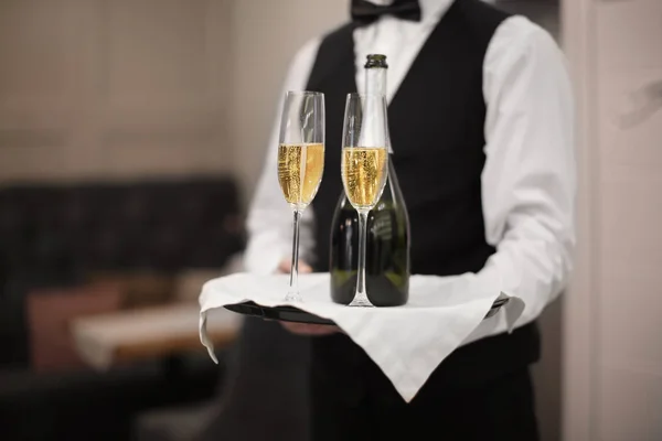 服务员拿着玻璃杯和香槟瓶室内的托盘 — 图库照片
