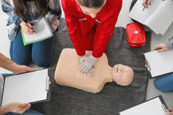 Woman demonstrating CPR on mannequin in first aid class