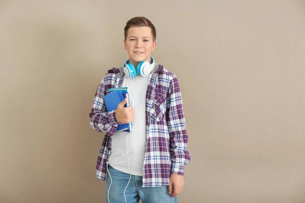 Adolescente con cuadernos y auriculares sobre fondo gris — Foto de Stock