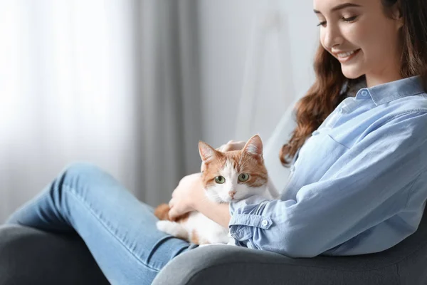 美丽的年轻女子与可爱的猫在扶手椅在家 — 图库照片