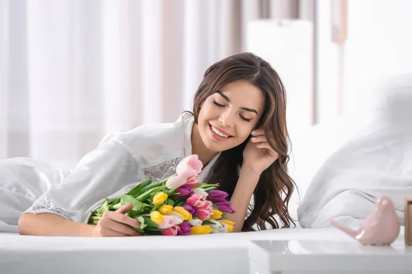 自宅のベッドにチューリップの花束の美女 — ストック写真