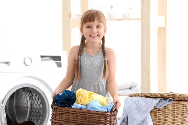Cute little girl with laundry basket indoors