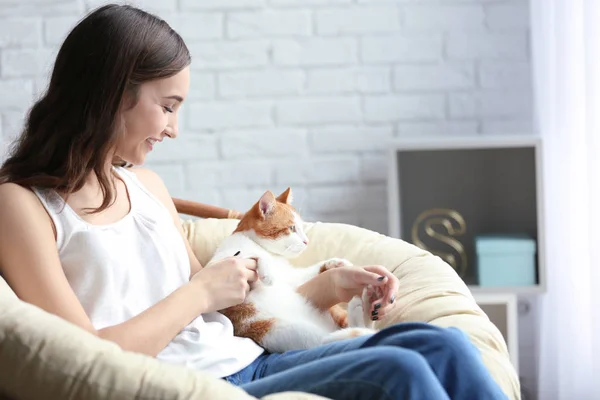 Hermosa mujer joven con lindo gato en sillón en casa —  Fotos de Stock