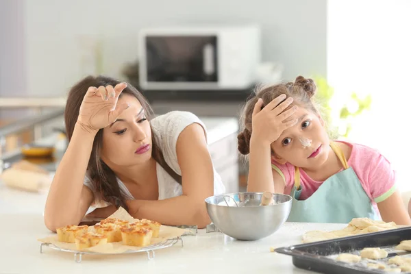 Tired mother and daughter after preparing dough indoors