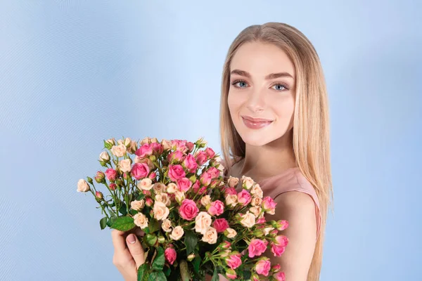 色の背景にバラの花束を持つ美しい若い女性 — ストック写真