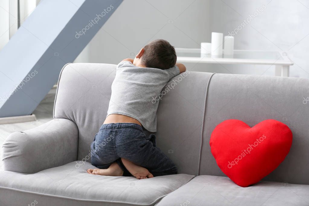 Little boy sitting on sofa at home. Child autism