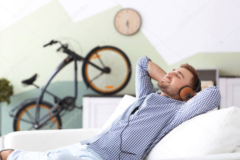 Young man listening to music while relaxing on sofa at home