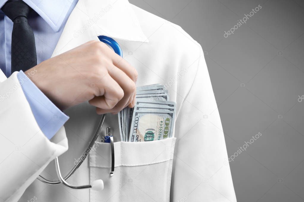 Doctor putting money in pocket on grey background. Corruption concept