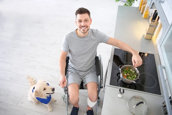 Man in rolstoel koken met hond — Stockfoto