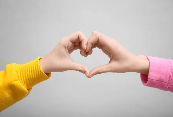 Persone che fanno il simbolo del cuore con le mani su sfondo chiaro — Foto Stock