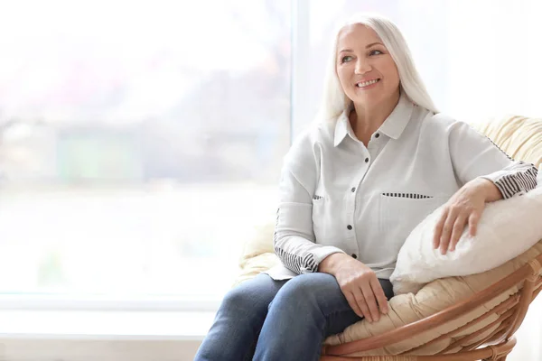 Portret van mooie rijpe vrouw zit in fauteuil thuis — Stockfoto