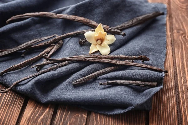 Bastoncini di vaniglia e fiore su tessuto, primo piano — Foto Stock