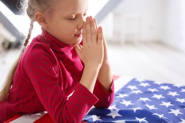 Sevimli küçük kız Amerikan bayrağı üzerinde dua