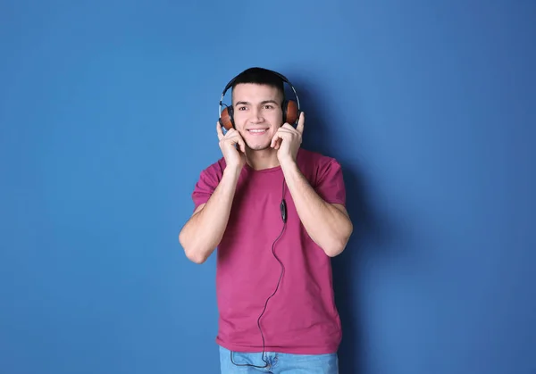 Hombre escuchando audiolibro a través de auriculares en el fondo de color —  Fotos de Stock