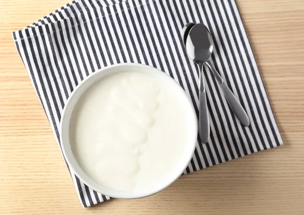 Smaczny jogurt w naczyniu na drewnianym stole — Zdjęcie stockowe