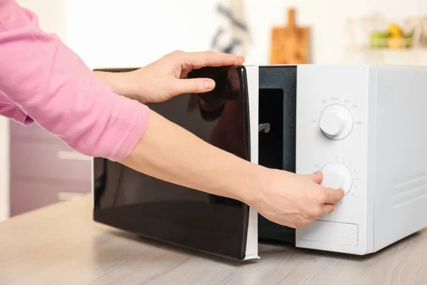 Woman heating food in microwave oven, closeup