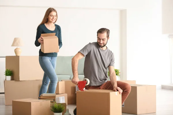 Young couple packing moving boxes, indoors — Stock Photo, Image
