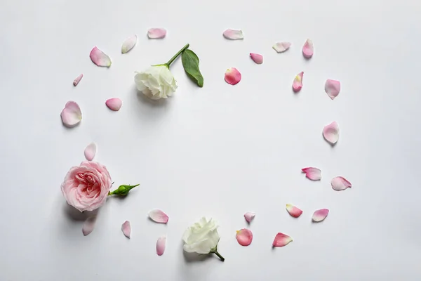 Rozenblaadjes en bloemen op lichte achtergrond, bovenaanzicht — Stockfoto