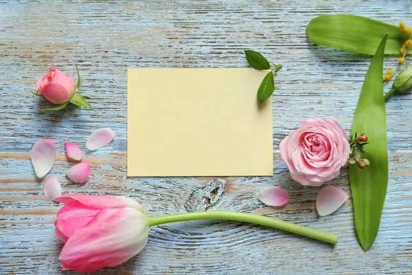 Hermosas flores y tarjeta vacía sobre fondo de madera — Foto de Stock