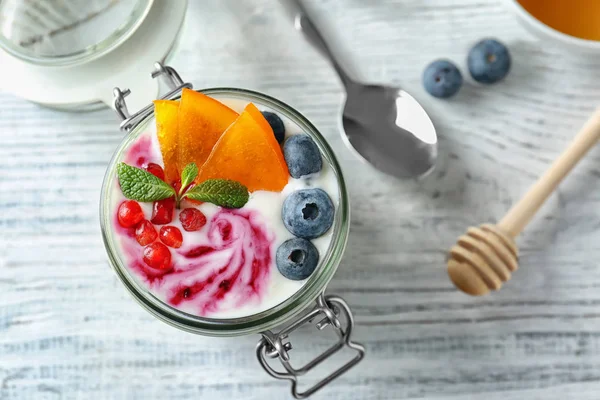Йогурт с фруктами в банке на деревянном столе — стоковое фото