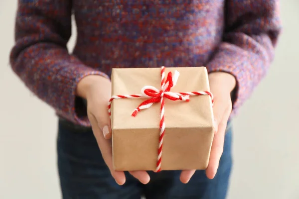 Frau hält Paket Geschenkbox auf hellem Hintergrund — Stockfoto