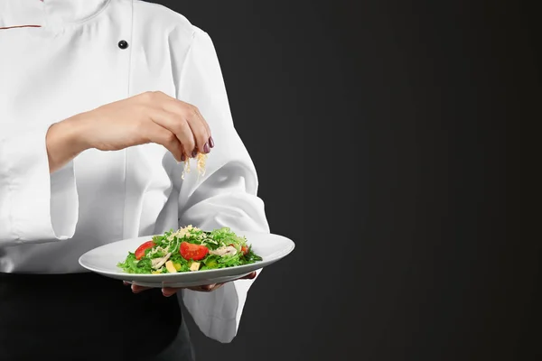 Chef femenino preparando sabrosa ensalada sobre fondo negro, primer plano —  Fotos de Stock