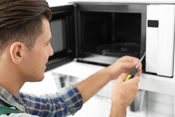 Giovanotto riparazione forno a microonde, primo piano — Foto Stock