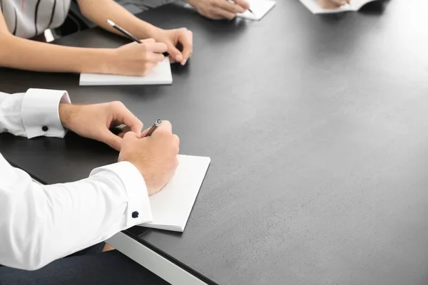 Jovem escrevendo em caderno na mesa em reunião de negócios, close-up. Conceito de unidade — Fotografia de Stock