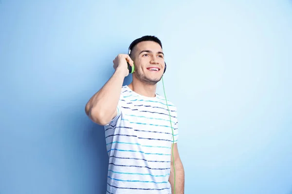 Hombre escuchando audiolibro a través de auriculares en el fondo de color —  Fotos de Stock