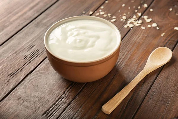 Smaczny jogurt w naczyniu na drewnianym stole — Zdjęcie stockowe