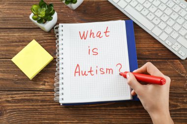 Otizm nedir metin yazma, kadın mı? Not Defteri'nde ahşap arka plan üzerinde