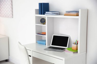 Dizüstü bilgisayar ve kitap yakın öğrencinin odada beyaz duvar tablo