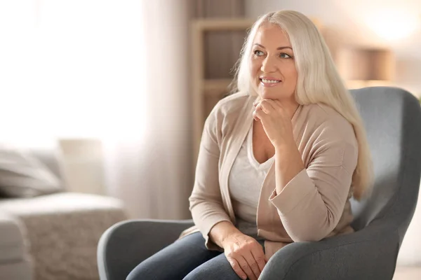 Portrait de belle femme mature assise dans un fauteuil à la maison — Photo