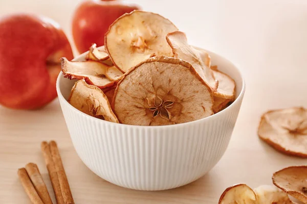 Bowl with tasty apple chips on wooden table