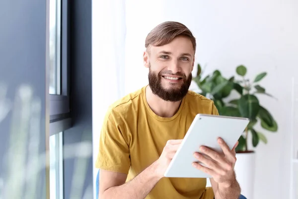 Портрет красивого бородатого мужчины с планшетным компьютером в помещении — стоковое фото