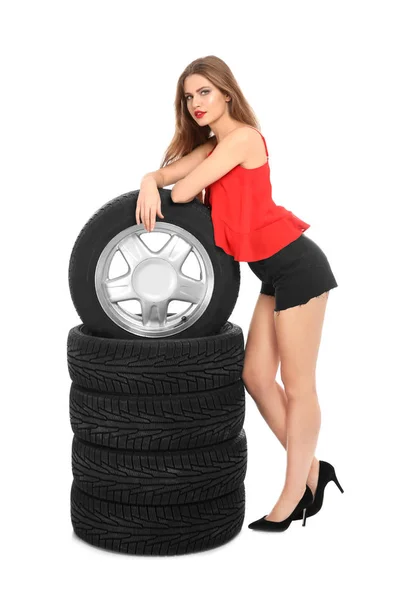年轻女子在诱人的装备与汽车轮胎白色背景 — 图库照片