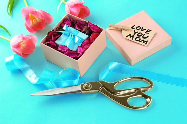 Composition with gift, flowers and scissors on color background. Greetings for Mother's day — Stock Photo, Image