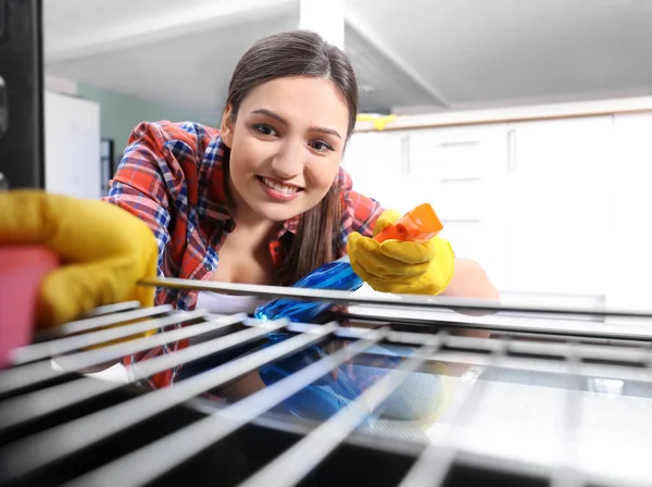 Jovem mulher limpando forno, vista de dentro — Fotografia de Stock