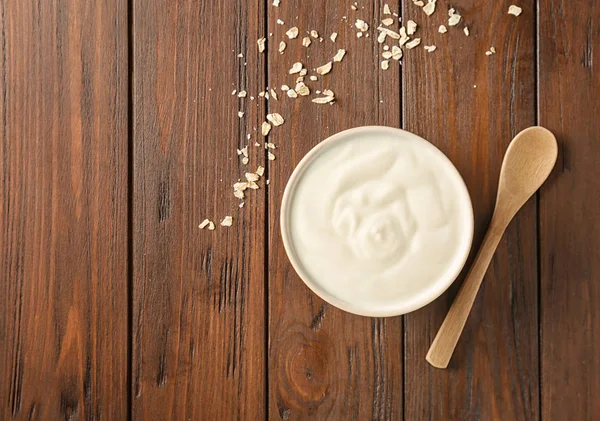 Tasty yogurt in dish on wooden table — Stock Photo, Image