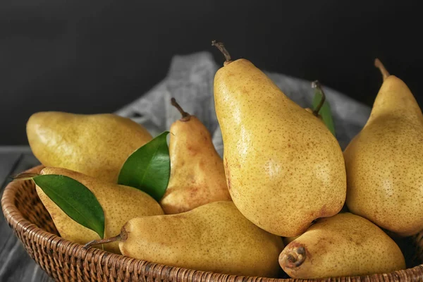 Wicker basket with fresh ripe pears on dark background — Stock Photo, Image