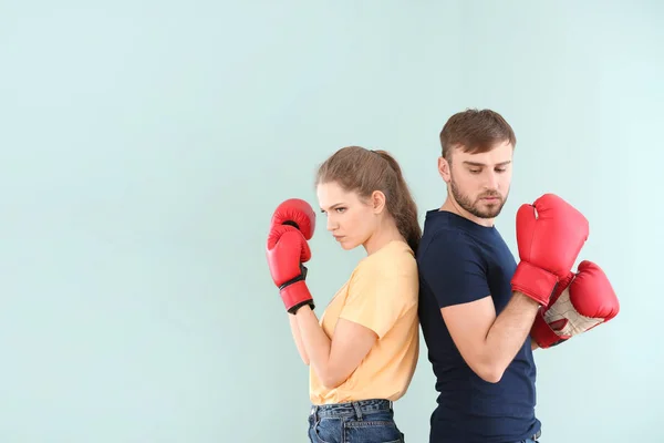 Pareja luchando en guantes de boxeo sobre fondo de color. Problemas en la relación —  Fotos de Stock