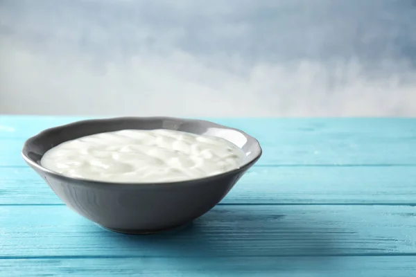 Tasty yogurt in dish on wooden table — Stock Photo, Image