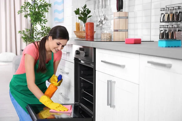 Wanita muda membersihkan oven di dapur — Stok Foto
