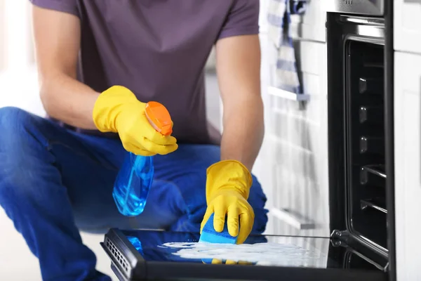 Schoonmaken van de oven in keuken, close-up man — Stockfoto