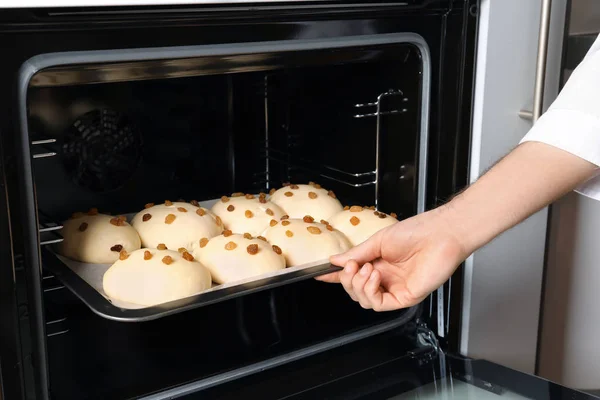 Man bakplaat met rauwe broodjes in de oven zetten — Stockfoto