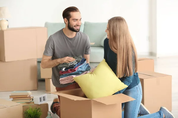 Casal jovem embalando caixas móveis no quarto — Fotografia de Stock