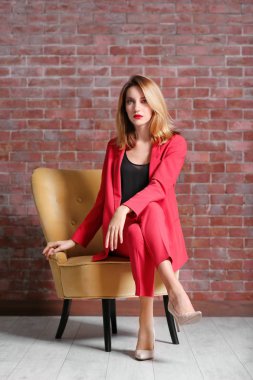 Güzel genç şık kadın koltuk duvara yakın oturan