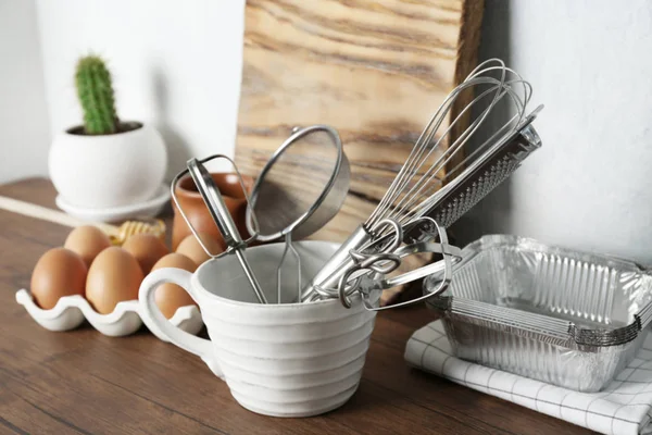 Tasse mit Küchenutensilien und Zutaten für die Zubereitung von Gebäck auf dem Tisch — Stockfoto