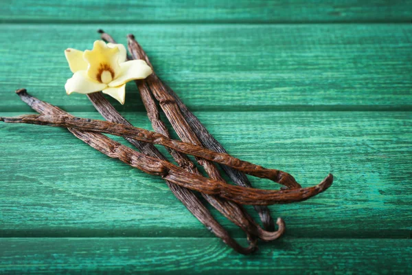 Palos de vainilla y flor sobre fondo de madera —  Fotos de Stock