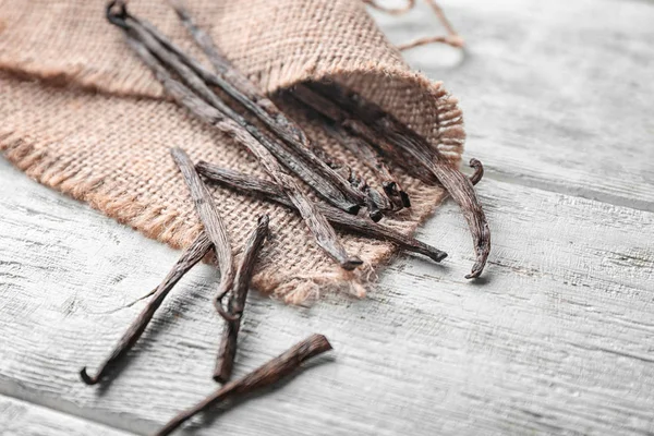 Vanilla sticks and sackcloth on table, closeup — Stock Photo, Image